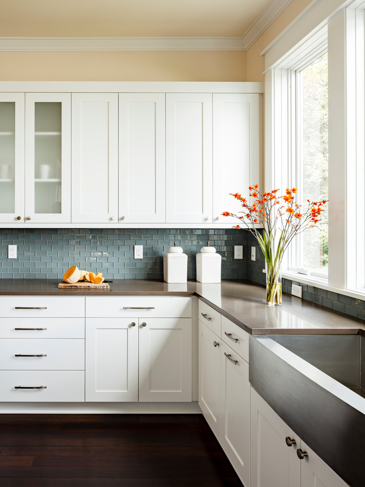 This is an example of a mid-sized transitional l-shaped kitchen in Portland with a farmhouse sink, blue splashback, white cabinets, shaker cabinets, quartz benchtops, brown benchtop, mosaic tile splashback, stainless steel appliances and dark hardwood floors.