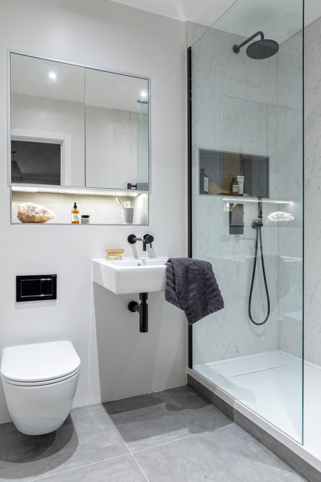 This is an example of a small scandinavian master bathroom in London with a drop-in tub, an open shower, a wall-mount toilet, white tile, porcelain tile, white walls, porcelain floors, a wall-mount sink and grey floor.