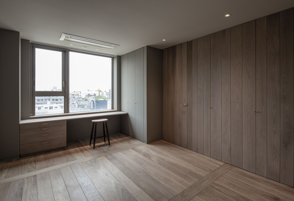Ejemplo de dormitorio principal y blanco moderno de tamaño medio sin chimenea con paredes grises, suelo de madera clara, suelo marrón, machihembrado y madera