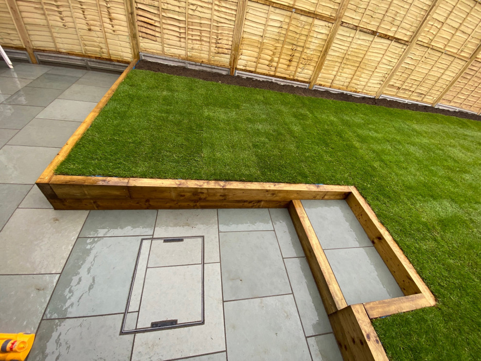 Mittelgroßer Moderner Garten im Sommer, hinter dem Haus mit Rasenkanten, direkter Sonneneinstrahlung, Pflastersteinen und Holzzaun in London