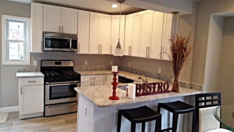 Small transitional u-shaped ceramic tile eat-in kitchen photo in Baltimore with an undermount sink, flat-panel cabinets, brown cabinets, granite countertops, brown backsplash, ceramic backsplash, black appliances and an island