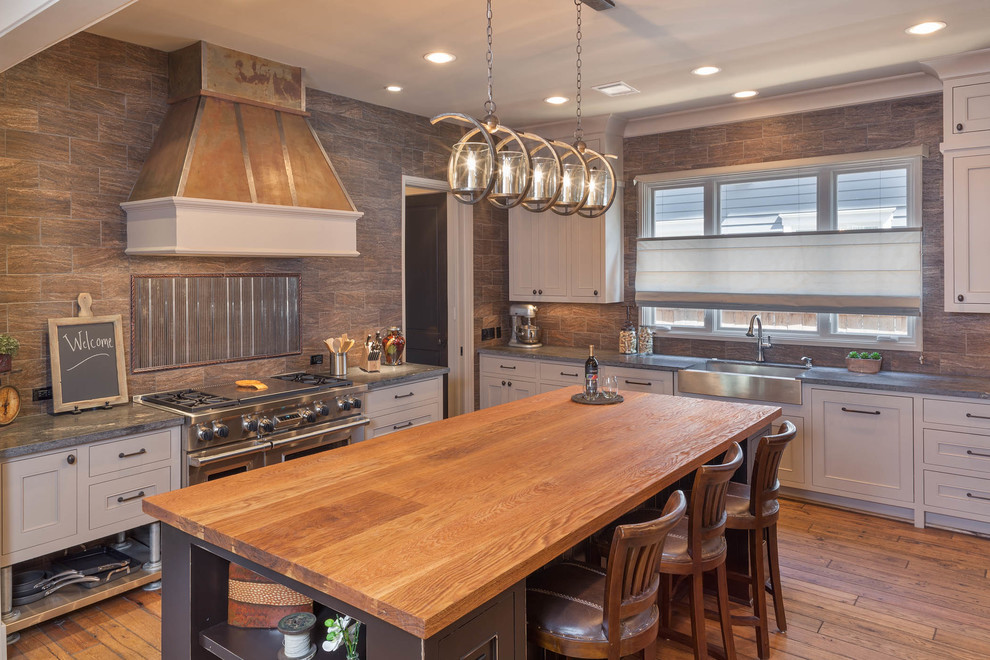 This is an example of an expansive industrial u-shaped separate kitchen in Houston with an undermount sink, shaker cabinets, white cabinets, granite benchtops, brown splashback, stone tile splashback, stainless steel appliances, medium hardwood floors, with island, brown floor and grey benchtop.