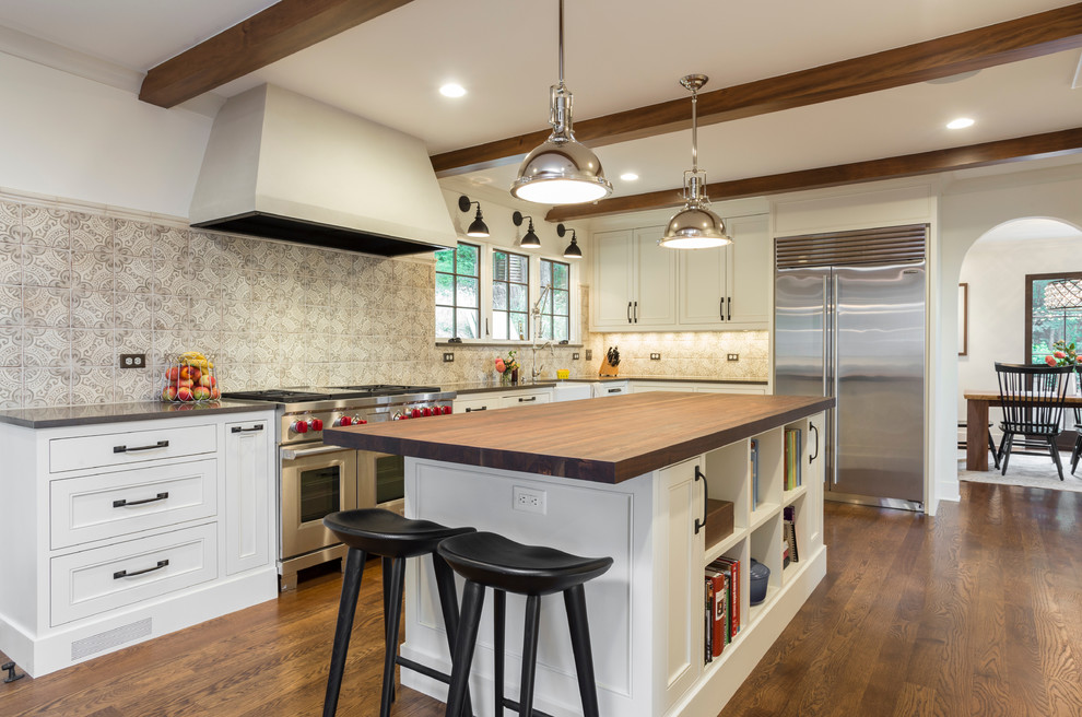 Inspiration for a large mediterranean l-shaped brown floor and medium tone wood floor open concept kitchen remodel in Portland with a farmhouse sink, recessed-panel cabinets, white cabinets, quartz countertops, gray backsplash, ceramic backsplash, stainless steel appliances and an island