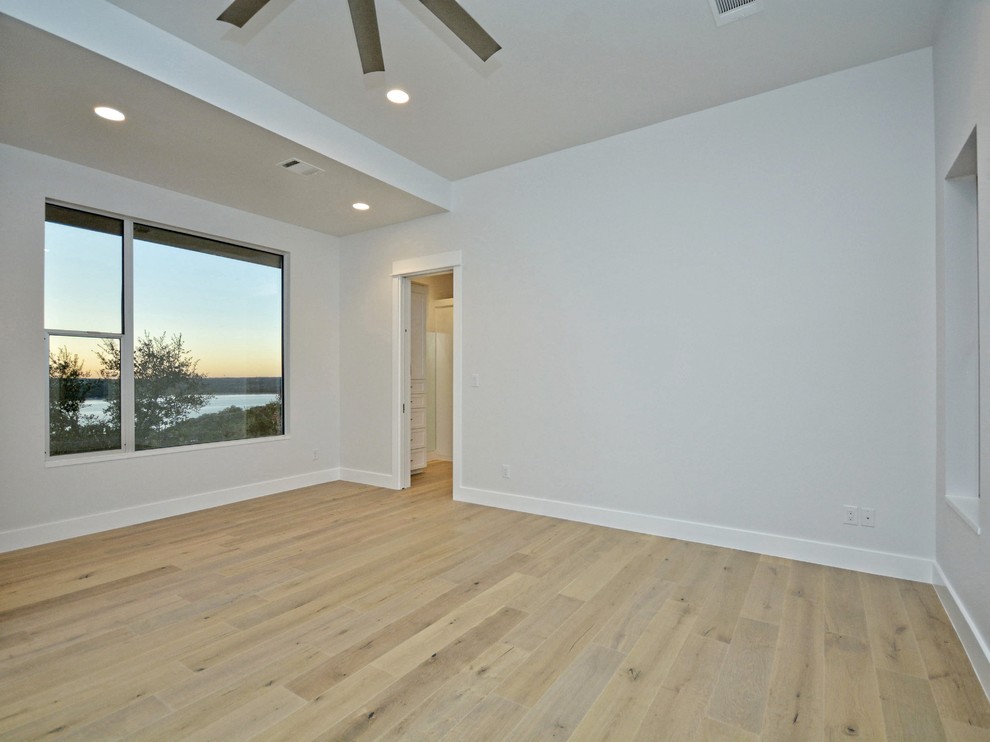 Photo of a large contemporary master bedroom in Austin with white walls, light hardwood floors and no fireplace.