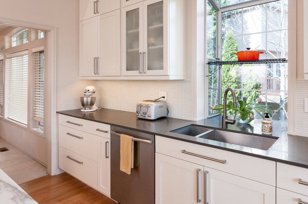 Mid-sized contemporary l-shaped open plan kitchen in Seattle with a double-bowl sink, shaker cabinets, yellow cabinets, marble benchtops, white splashback, glass tile splashback, stainless steel appliances, light hardwood floors and with island.