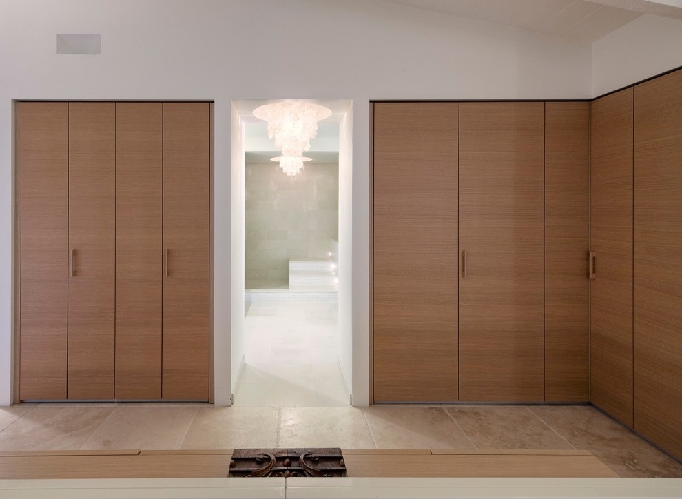 This is an example of a large contemporary men's dressing room in San Luis Obispo with flat-panel cabinets, medium wood cabinets, limestone floors and beige floor.