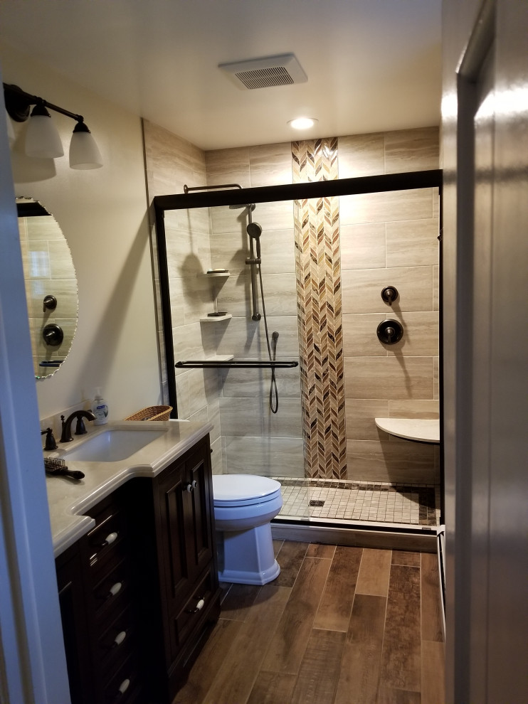 Design ideas for a mid-sized traditional master bathroom in Baltimore with furniture-like cabinets, brown cabinets, a two-piece toilet, beige tile, glass sheet wall, beige walls, porcelain floors, an undermount sink, marble benchtops, brown floor, beige benchtops, a shower seat, a double vanity and a built-in vanity.