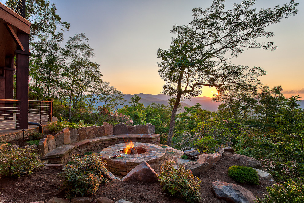 Photo of a large country backyard full sun xeriscape for summer in Other with a fire feature, natural stone pavers and a stone fence.