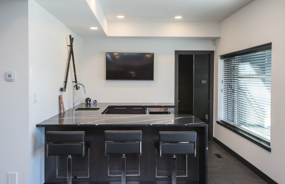 Photo of a contemporary u-shaped wet bar in Other with an undermount sink, flat-panel cabinets, black cabinets, quartz benchtops, ceramic floors, grey floor and black benchtop.