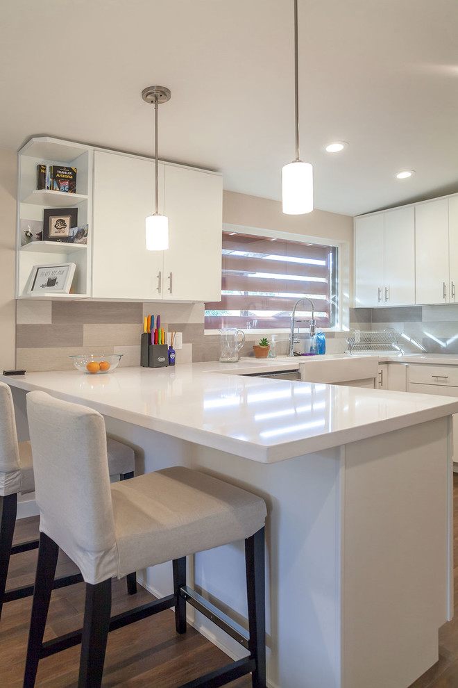 Transitional u-shaped porcelain tile open concept kitchen photo in Phoenix with a farmhouse sink, shaker cabinets, white cabinets, quartz countertops, multicolored backsplash, porcelain backsplash, stainless steel appliances and an island