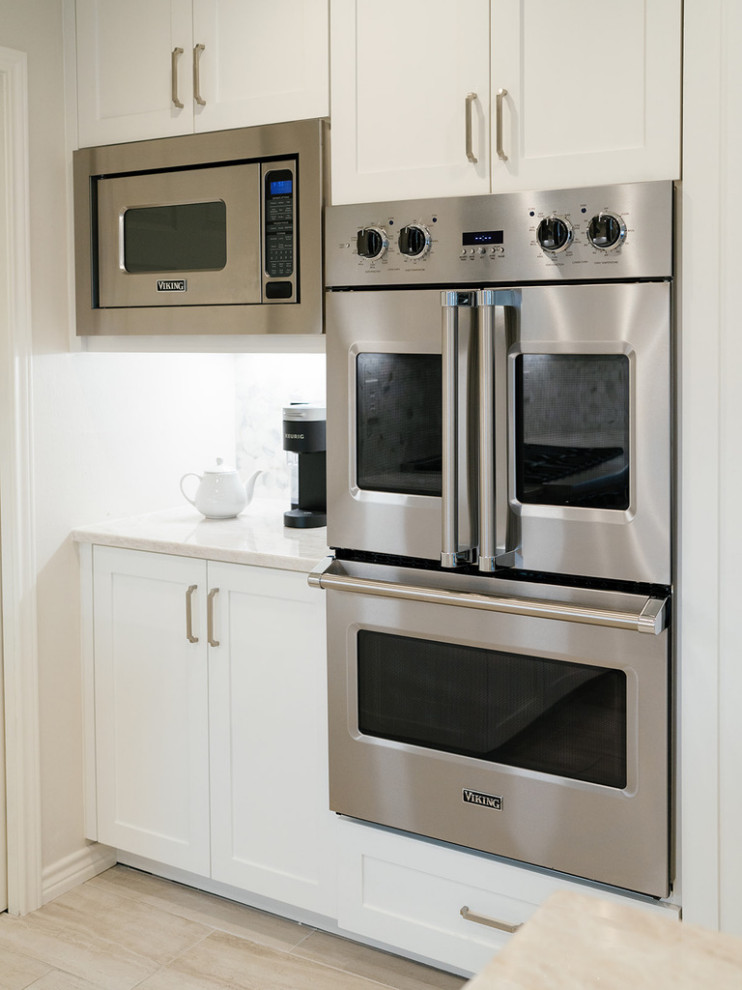 Enclosed kitchen - large transitional u-shaped medium tone wood floor and brown floor enclosed kitchen idea in Dallas with an undermount sink, raised-panel cabinets, beige cabinets, quartzite countertops, white backsplash, marble backsplash, stainless steel appliances, an island and beige countertops
