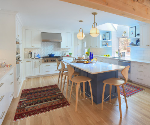 Bright, accessible kitchen with white RTA cabinets, a blue island, pendant lights, and wood stools—ideal for aging in place.