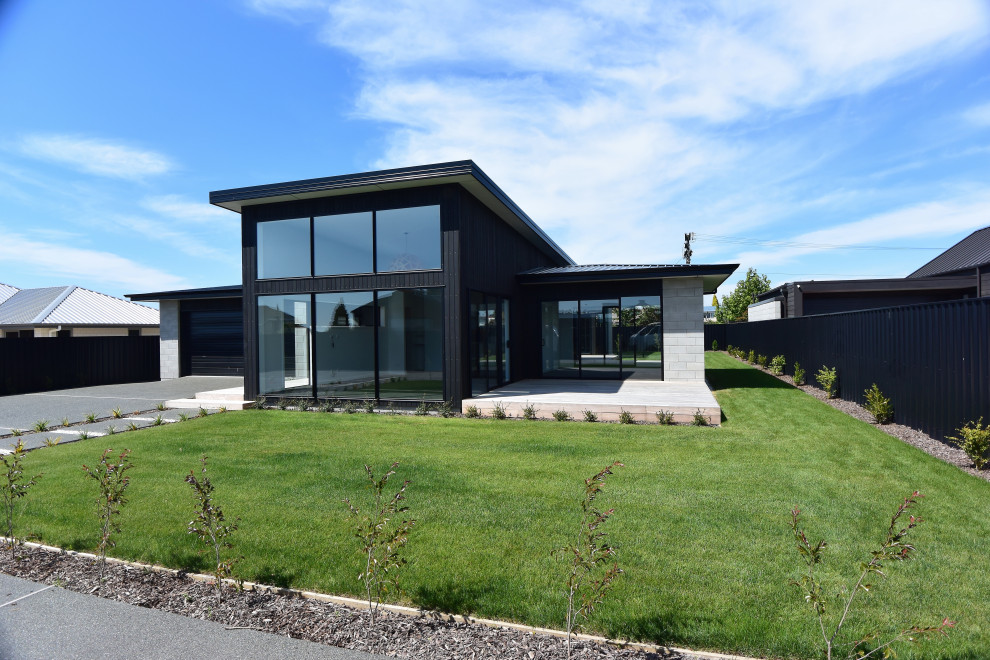 Modern black concrete exterior home idea with a black roof