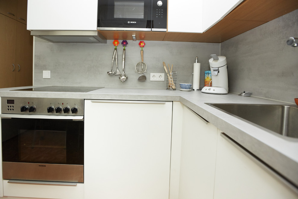 Mid-sized contemporary separate kitchen in Munich with an undermount sink, white cabinets, laminate benchtops, grey splashback and grey benchtop.