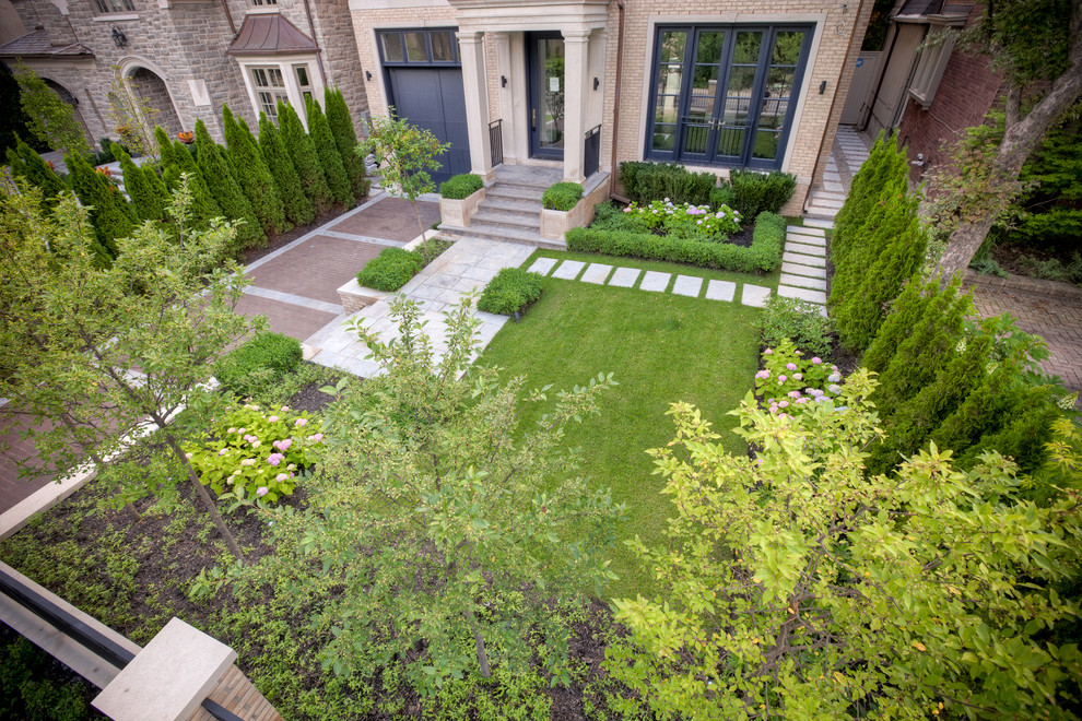 Design ideas for a small contemporary front yard full sun driveway for summer in Toronto with a retaining wall and natural stone pavers.