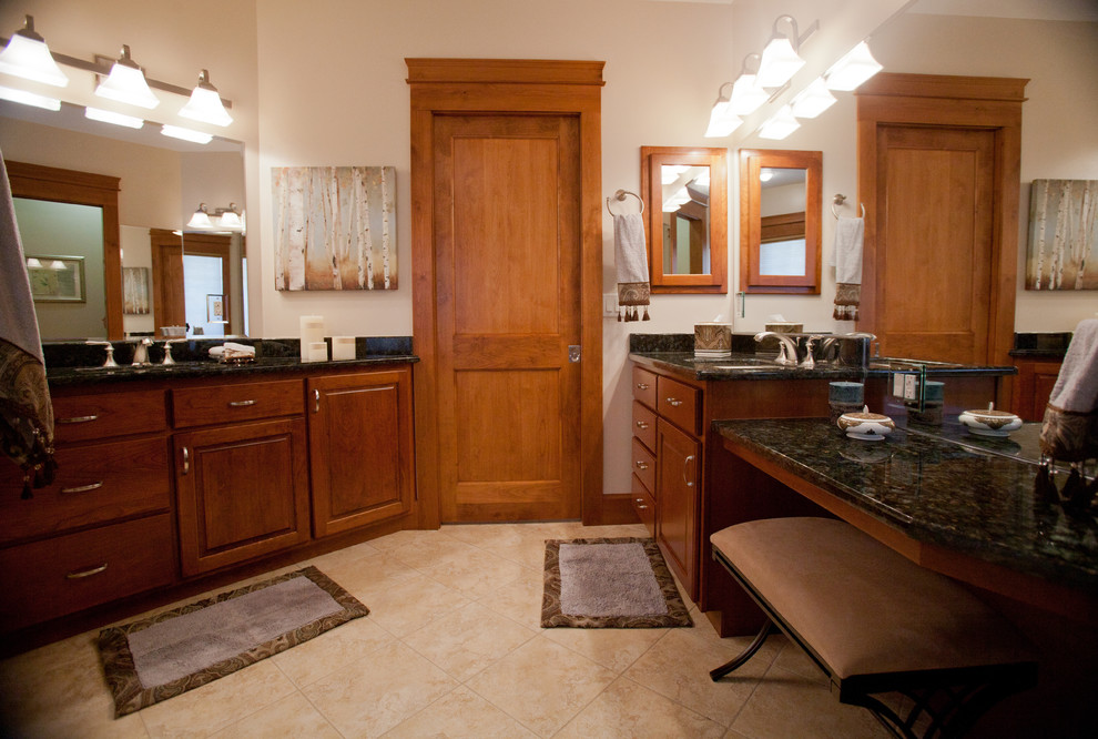 Design ideas for a mid-sized traditional master bathroom in Other with an undermount sink, raised-panel cabinets, brown cabinets, granite benchtops, beige tile, porcelain tile, beige walls and porcelain floors.