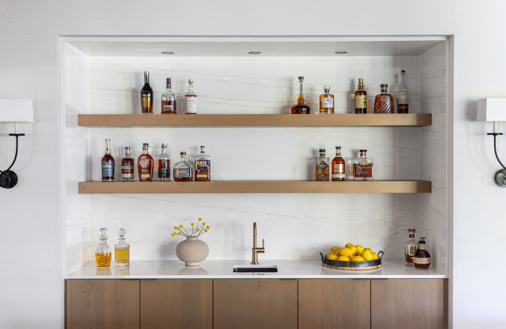Example of a small trendy single-wall medium tone wood floor and brown floor wet bar design in DC Metro with an undermount sink, flat-panel cabinets, medium tone wood cabinets, quartz countertops, white backsplash, quartz backsplash and white countertops