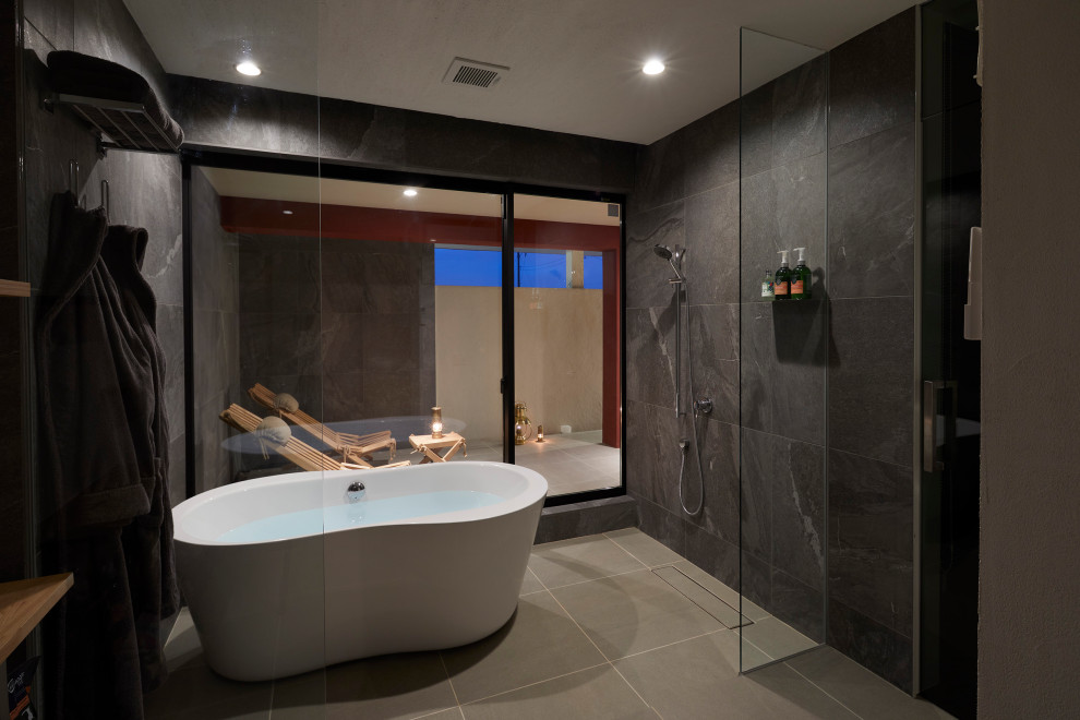 Ispirazione per una stanza da bagno padronale minimalista con vasca freestanding, doccia aperta, piastrelle nere, piastrelle in gres porcellanato e doccia aperta