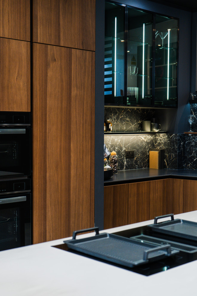 Photo of a medium sized modern l-shaped open plan kitchen in London with a built-in sink, glass-front cabinets, black cabinets, marble worktops, black splashback, stone slab splashback, black appliances, porcelain flooring, an island, grey floors and black worktops.