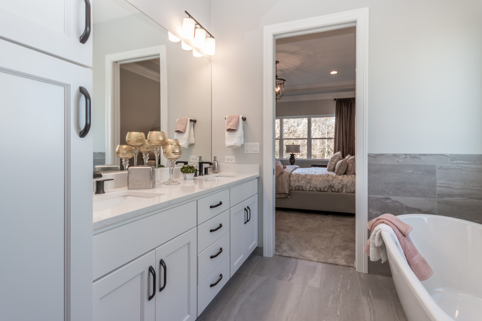 Mid-sized transitional master bathroom in Chicago with shaker cabinets, white cabinets, a freestanding tub, an alcove shower, a two-piece toilet, gray tile, porcelain tile, grey walls, porcelain floors, an undermount sink, engineered quartz benchtops, grey floor, a sliding shower screen and white benchtops.