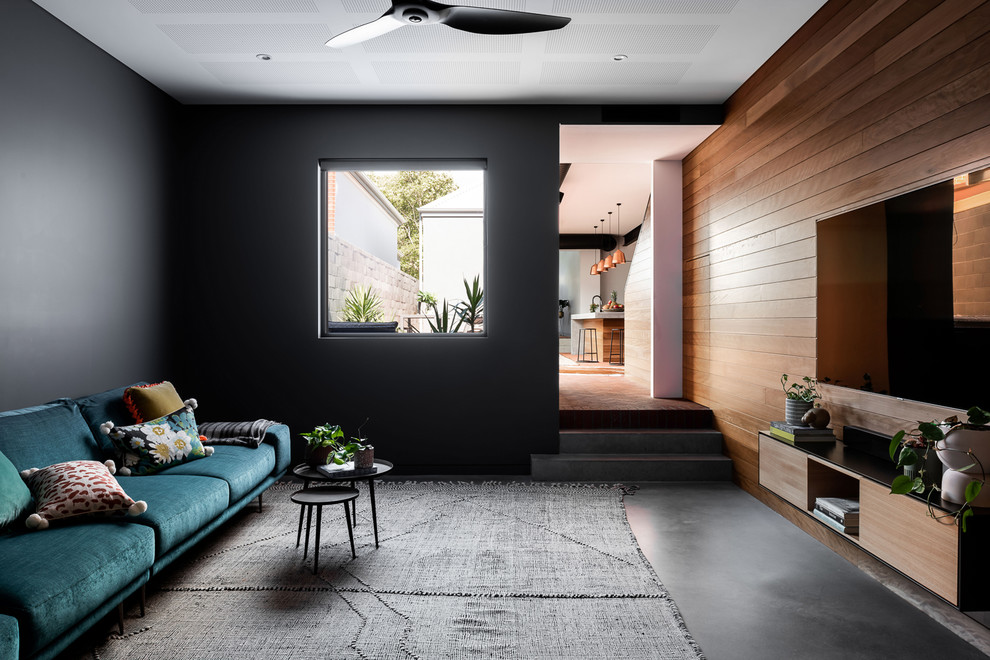 Photo of a mid-sized industrial enclosed living room in Perth with grey walls, concrete floors, grey floor, no fireplace and a wall-mounted tv.