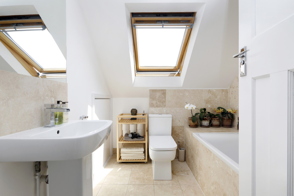 Photo of a small contemporary ensuite bathroom in Sussex with a built-in bath, a shower/bath combination, a two-piece toilet, beige tiles, ceramic tiles, white walls, ceramic flooring, a pedestal sink, beige floors, a single sink and a drop ceiling.
