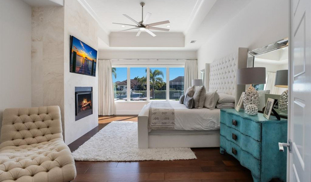 Photo of an expansive contemporary master bedroom in Tampa with white walls, light hardwood floors, a standard fireplace and coffered.