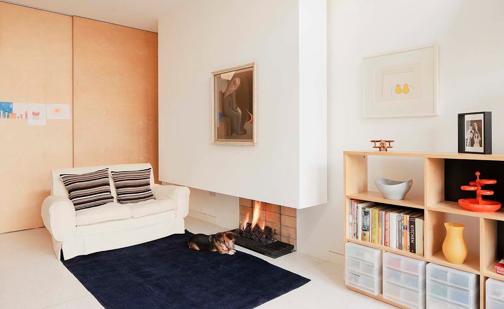Mid-sized scandinavian open concept living room in Dublin with a library, white walls, no tv, concrete floors, a hanging fireplace, a brick fireplace surround and white floor.