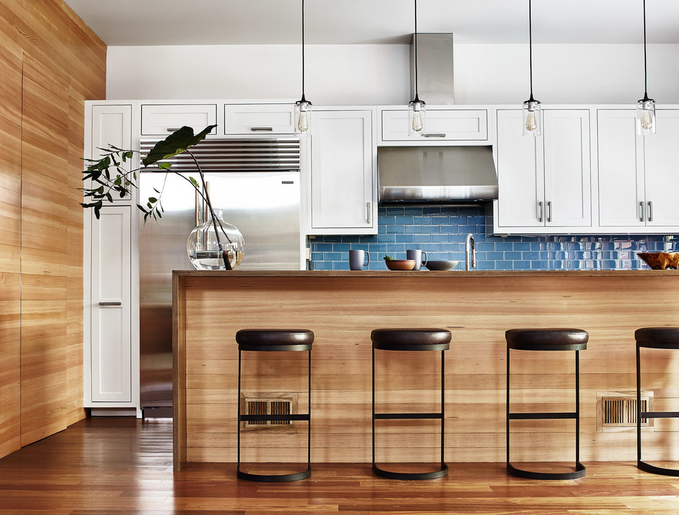 Inspiration for a transitional galley kitchen in San Francisco with shaker cabinets, white cabinets, blue splashback, stainless steel appliances, medium hardwood floors, with island and brown floor.