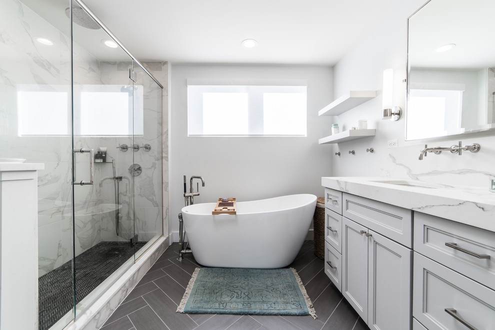 This is an example of a mid-sized contemporary master bathroom in Chicago with recessed-panel cabinets, grey cabinets, an alcove tub, a corner shower, a one-piece toilet, gray tile, marble, white walls, dark hardwood floors, an undermount sink, marble benchtops, brown floor, a hinged shower door and white benchtops.
