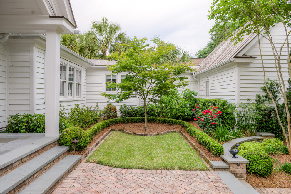 This is an example of an expansive country courtyard full sun formal garden in Charleston with brick pavers.