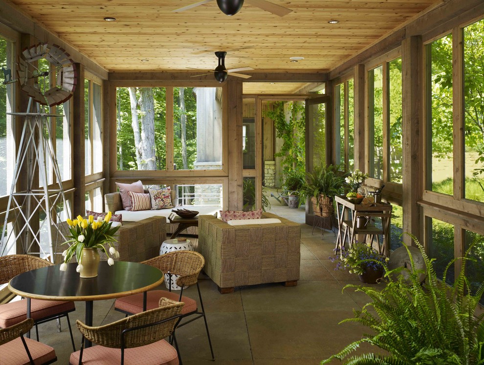 Expansive country backyard verandah in Chicago with natural stone pavers and a roof extension.