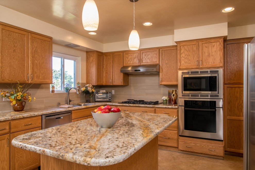 Photo of a traditional u-shaped eat-in kitchen in San Diego with a drop-in sink, recessed-panel cabinets, medium wood cabinets, granite benchtops, beige splashback, stone tile splashback and stainless steel appliances.