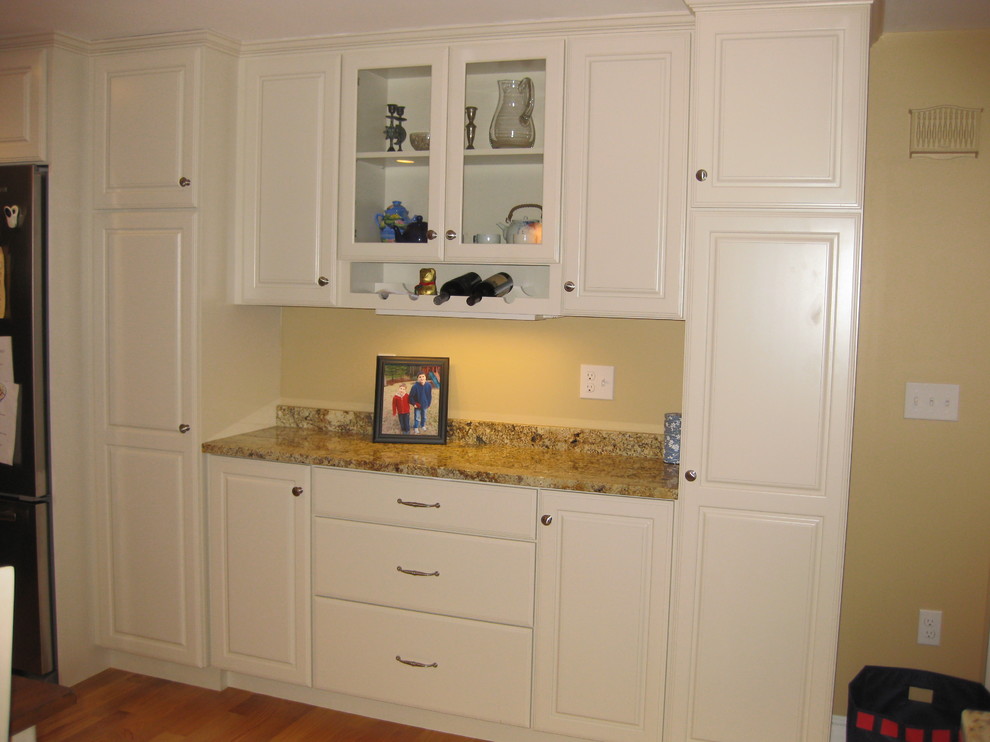 Transitional l-shaped light wood floor eat-in kitchen photo in Boston with raised-panel cabinets, white cabinets, granite countertops, stainless steel appliances, an undermount sink, beige backsplash, ceramic backsplash and an island