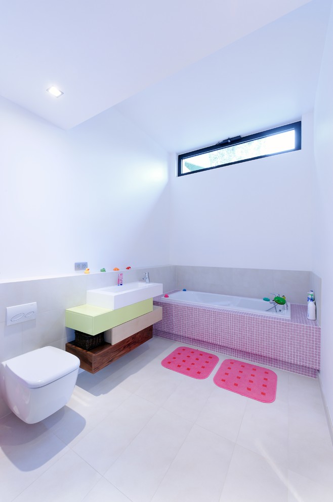 Inspiration pour salle de bain for enfant With une baignoire encastrée, WC suspendus, un carrelage gris, un mur blanc, un sol en carrelage de céramique and une vasque.