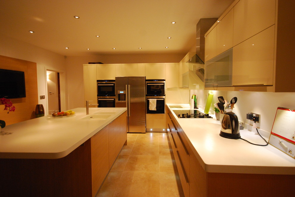 Photo of a contemporary kitchen in Other with a drop-in sink, flat-panel cabinets, light wood cabinets, solid surface benchtops, white splashback and panelled appliances.