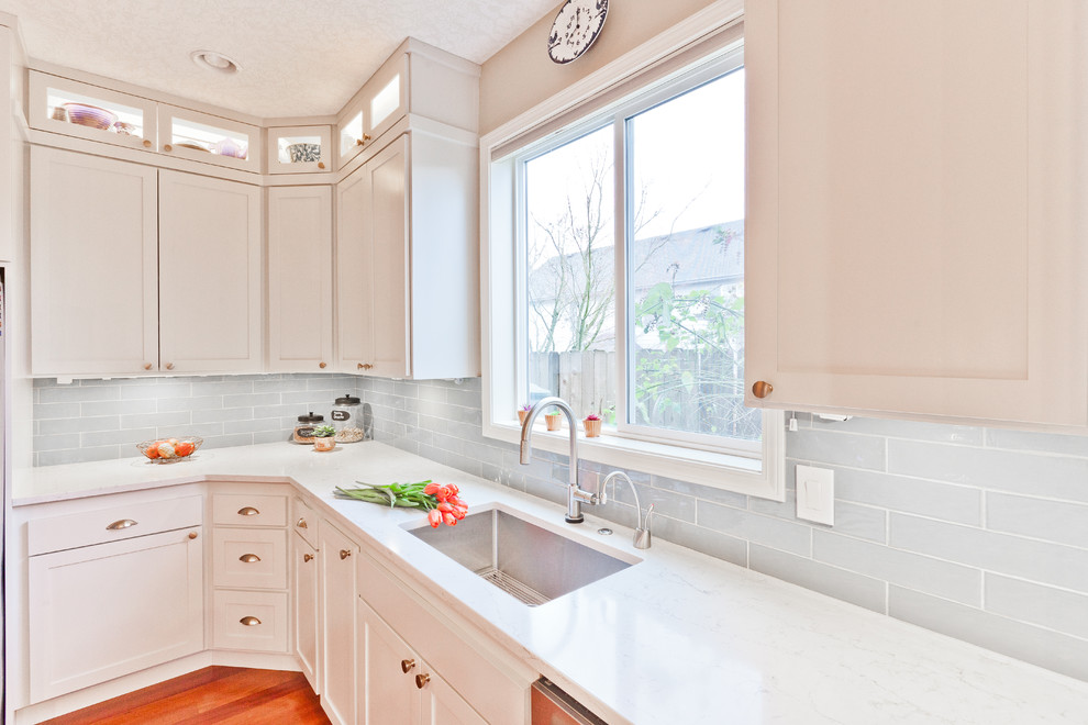 Photo of a mid-sized transitional l-shaped open plan kitchen in Portland with an undermount sink, shaker cabinets, grey cabinets, quartz benchtops, blue splashback, ceramic splashback, stainless steel appliances, medium hardwood floors, with island, red floor and white benchtop.