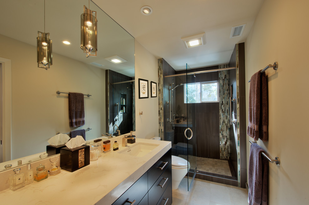 This is an example of a mid-sized contemporary bathroom in San Francisco with an undermount sink, flat-panel cabinets, brown cabinets, engineered quartz benchtops, an alcove shower, a one-piece toilet, gray tile, porcelain tile, beige walls and porcelain floors.