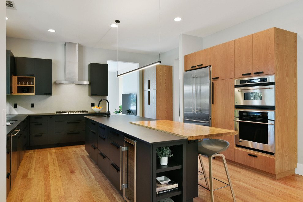 Design ideas for a large contemporary u-shaped separate kitchen in San Francisco with a double-bowl sink, flat-panel cabinets, grey splashback, stone slab splashback, stainless steel appliances, light hardwood floors, with island, black benchtop, medium wood cabinets and beige floor.