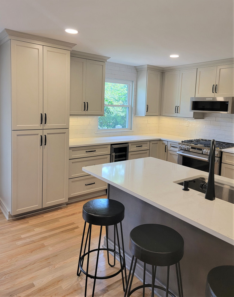 Inspiration for a mid-sized transitional l-shaped medium tone wood floor and yellow floor eat-in kitchen remodel with an undermount sink, flat-panel cabinets, gray cabinets, quartz countertops, white backsplash, ceramic backsplash, stainless steel appliances, an island and white countertops
