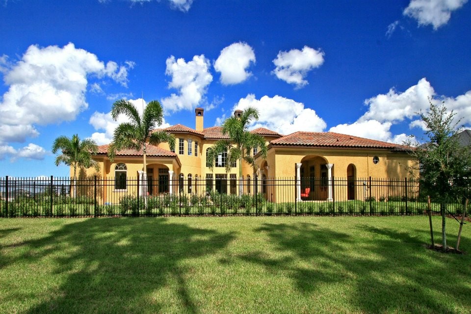 Photo of a large mediterranean two-storey stucco yellow house exterior in Orlando with a hip roof and a tile roof.