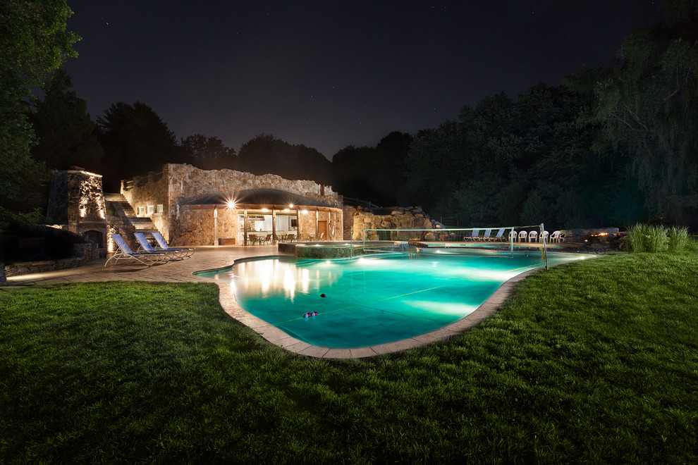Mid-sized country side yard custom-shaped natural pool in DC Metro with natural stone pavers and a hot tub.