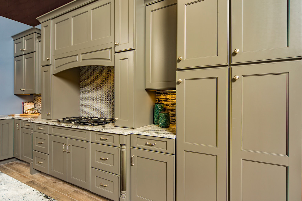 Example of a mid-sized classic l-shaped medium tone wood floor and brown floor kitchen design with shaker cabinets, brown cabinets, granite countertops, multicolored backsplash, mosaic tile backsplash and an island