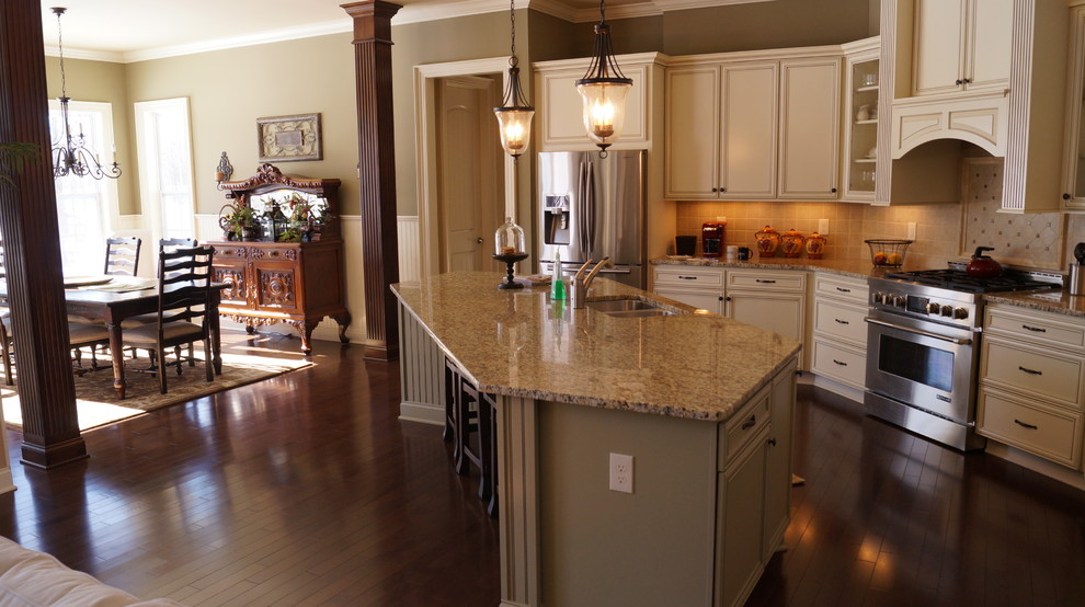 Example of a transitional u-shaped dark wood floor eat-in kitchen design in Columbus with an undermount sink, recessed-panel cabinets, green cabinets, granite countertops, beige backsplash, stone tile backsplash, stainless steel appliances and an island