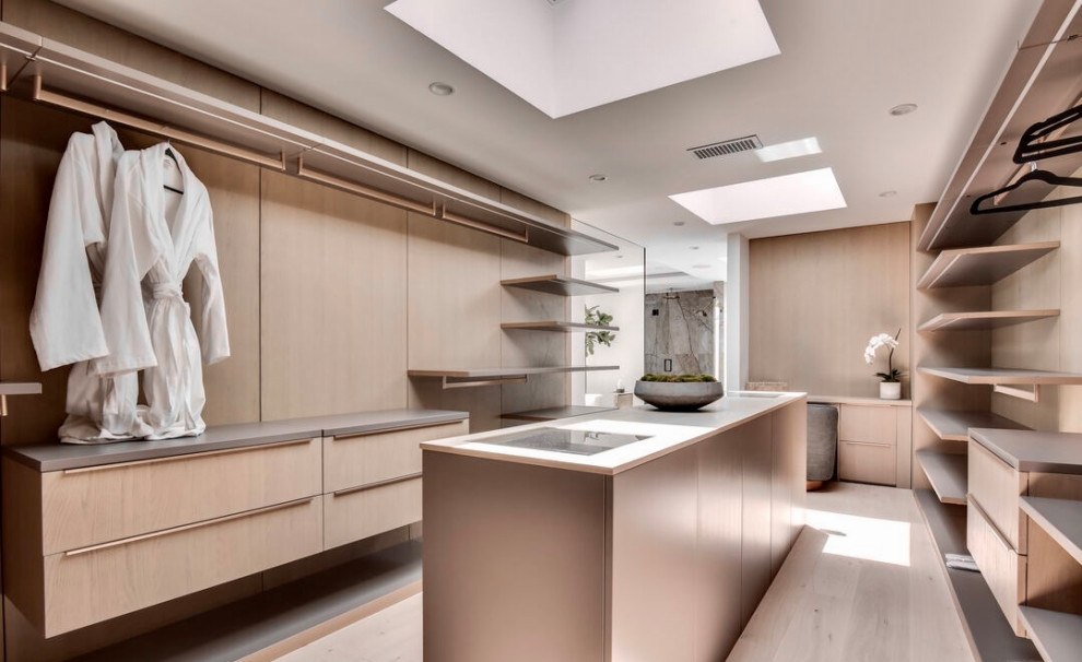 Inspiration for an expansive contemporary gender neutral dressing room in Los Angeles with flat-panel cabinets, light wood cabinets, light hardwood flooring, beige floors and feature lighting.