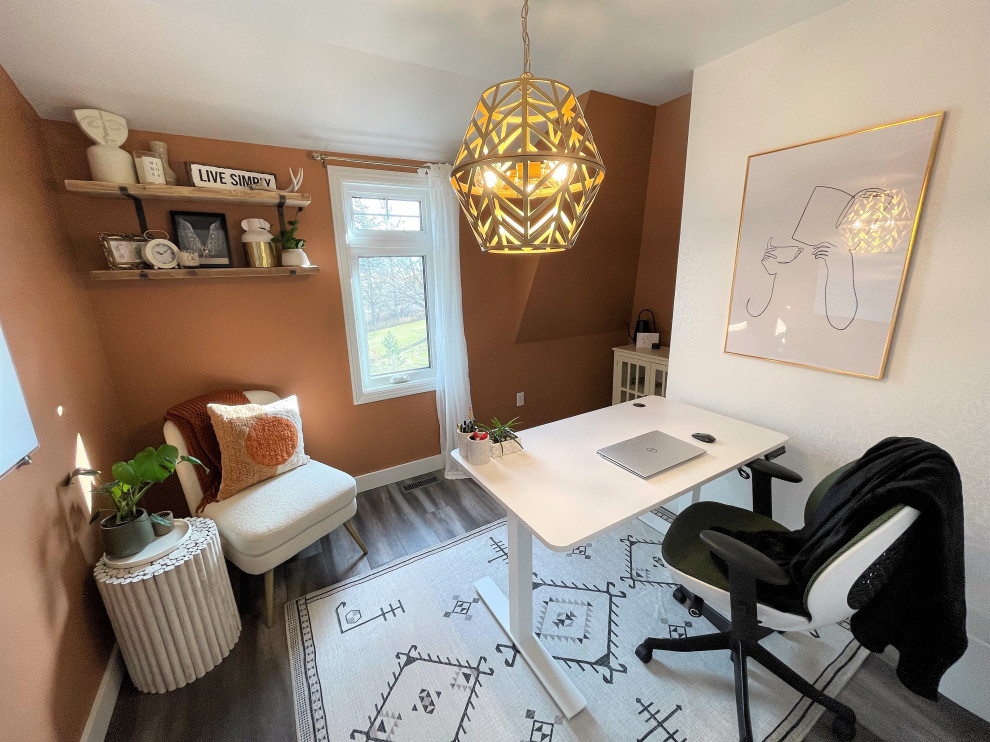 Imagen de despacho de estilo de casa de campo pequeño sin chimenea con parades naranjas, suelo laminado, escritorio independiente, suelo gris y papel pintado