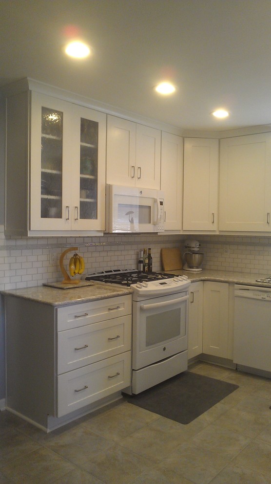 Photo of a small transitional u-shaped eat-in kitchen in Other with an undermount sink, recessed-panel cabinets, white cabinets, quartz benchtops, white splashback, subway tile splashback, white appliances, ceramic floors and no island.