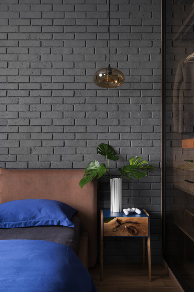 На фото: маленькая хозяйская спальня в стиле лофт с серыми стенами, полом из керамогранита, коричневым полом, кирпичными стенами и акцентной стеной для на участке и в саду