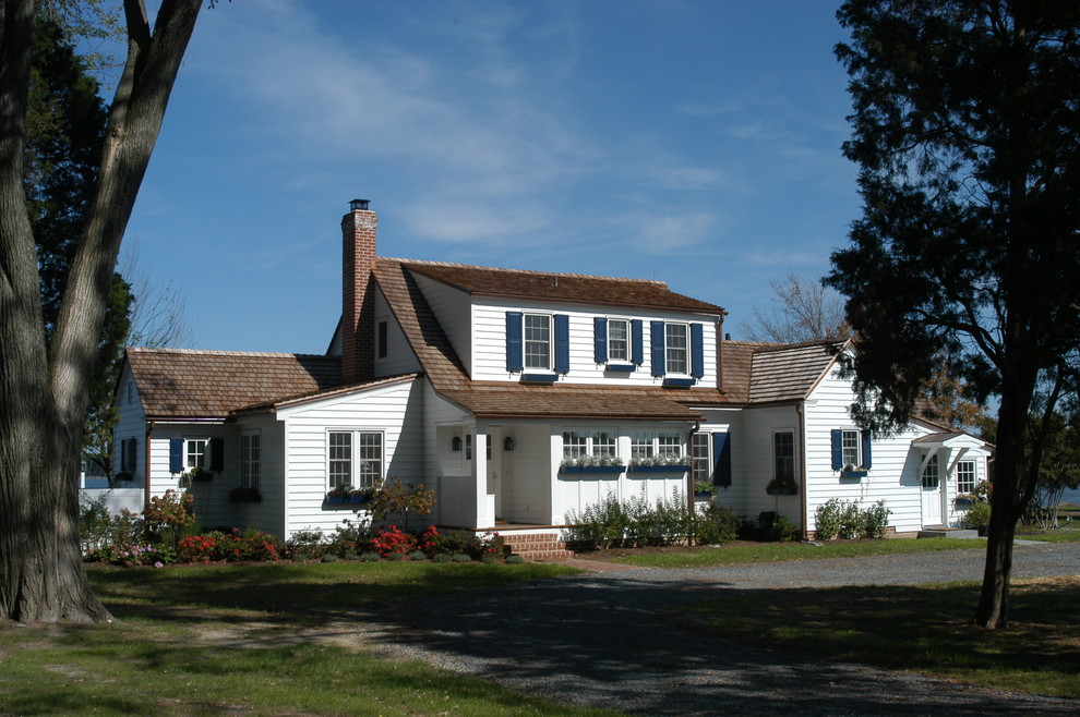 This is an example of a large country two-storey white exterior in DC Metro with wood siding.