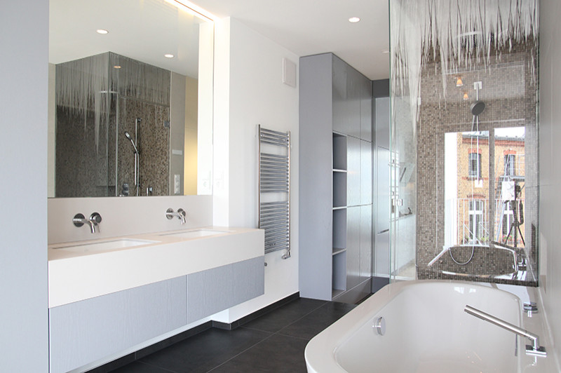 Example of a mid-sized trendy master black and white tile and ceramic tile ceramic tile, gray floor and double-sink bathroom design in Berlin with flat-panel cabinets, blue cabinets, a wall-mount toilet, white walls, a drop-in sink, solid surface countertops, a hinged shower door, white countertops and a built-in vanity
